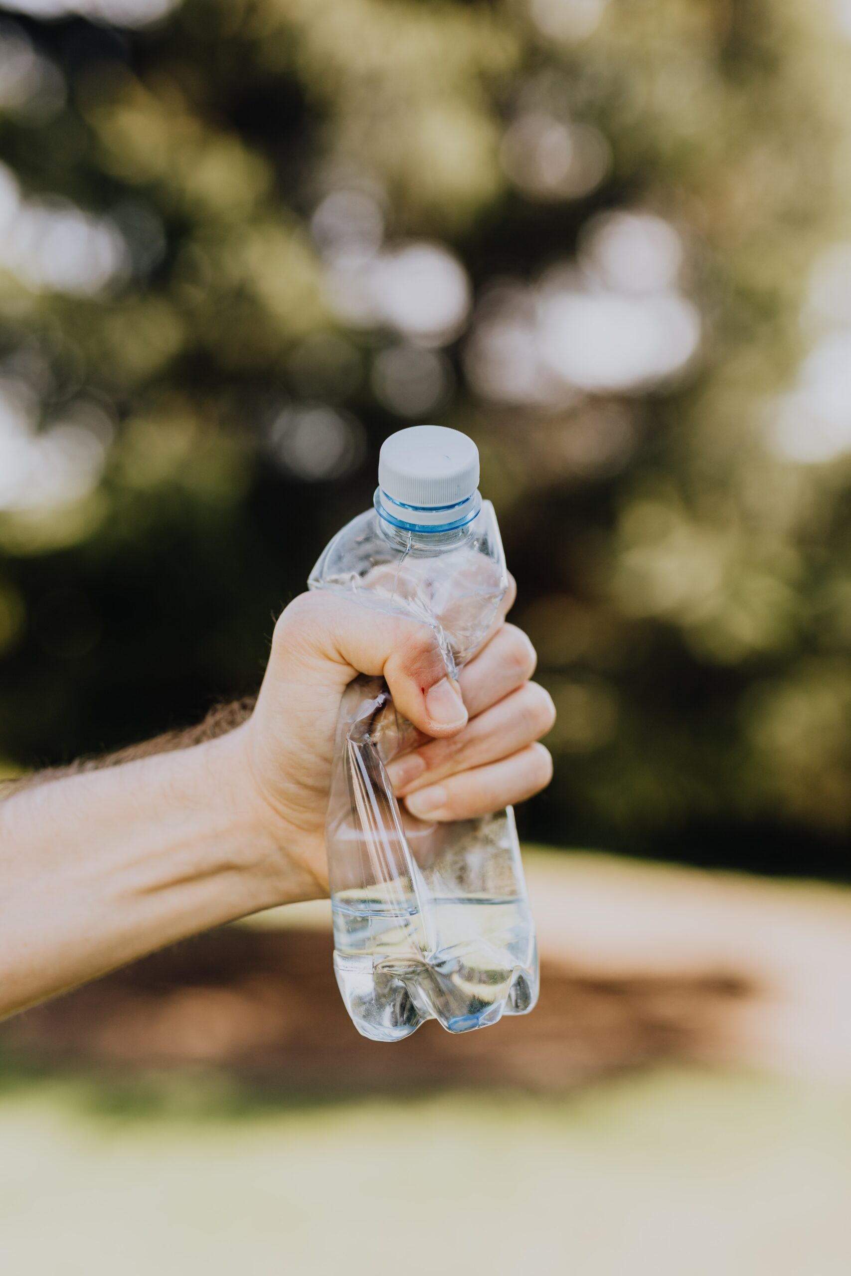 Hand clenching an empty clear plastic water bottle