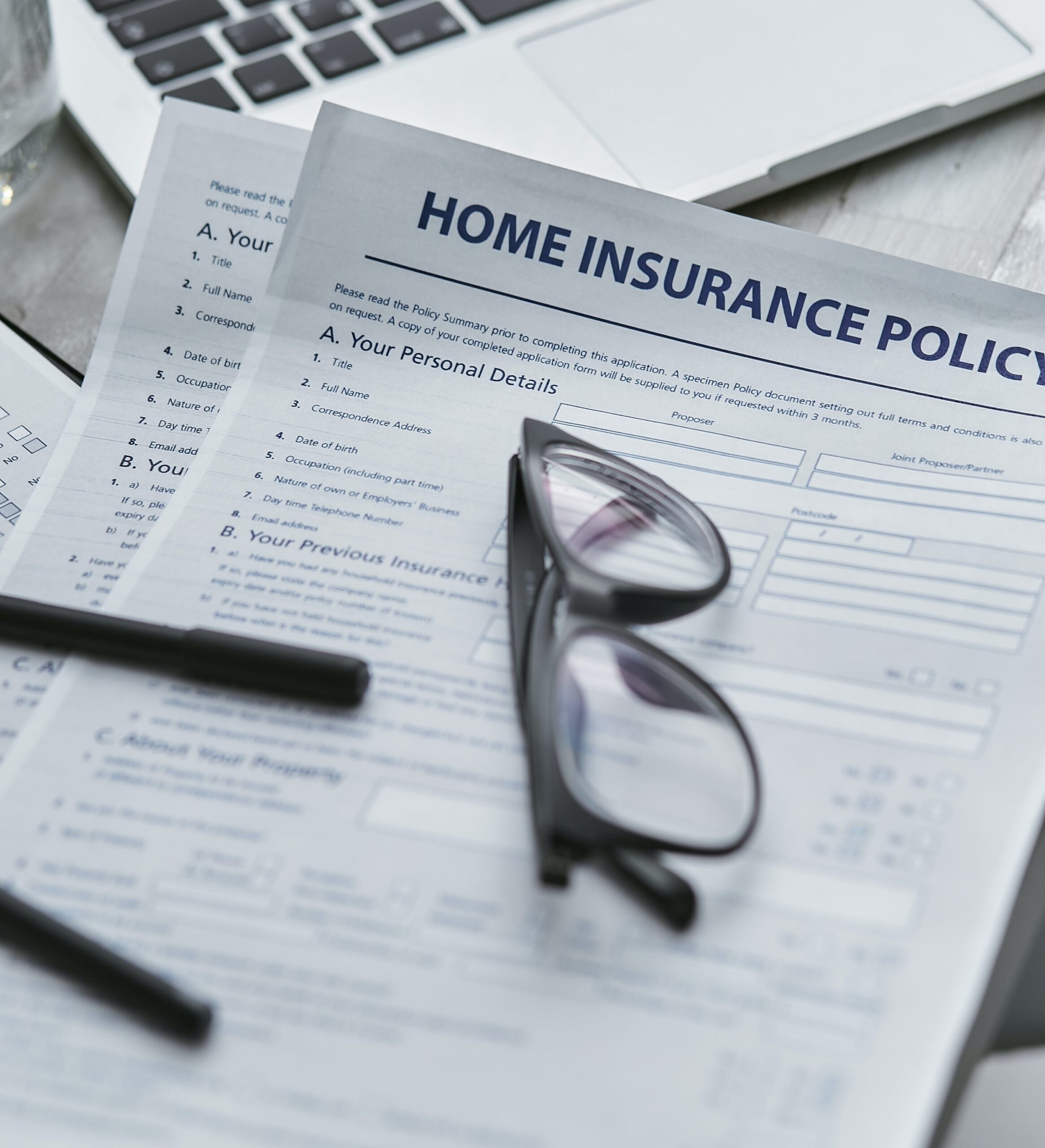 Glasses on top of paperwork with title home insurance policy