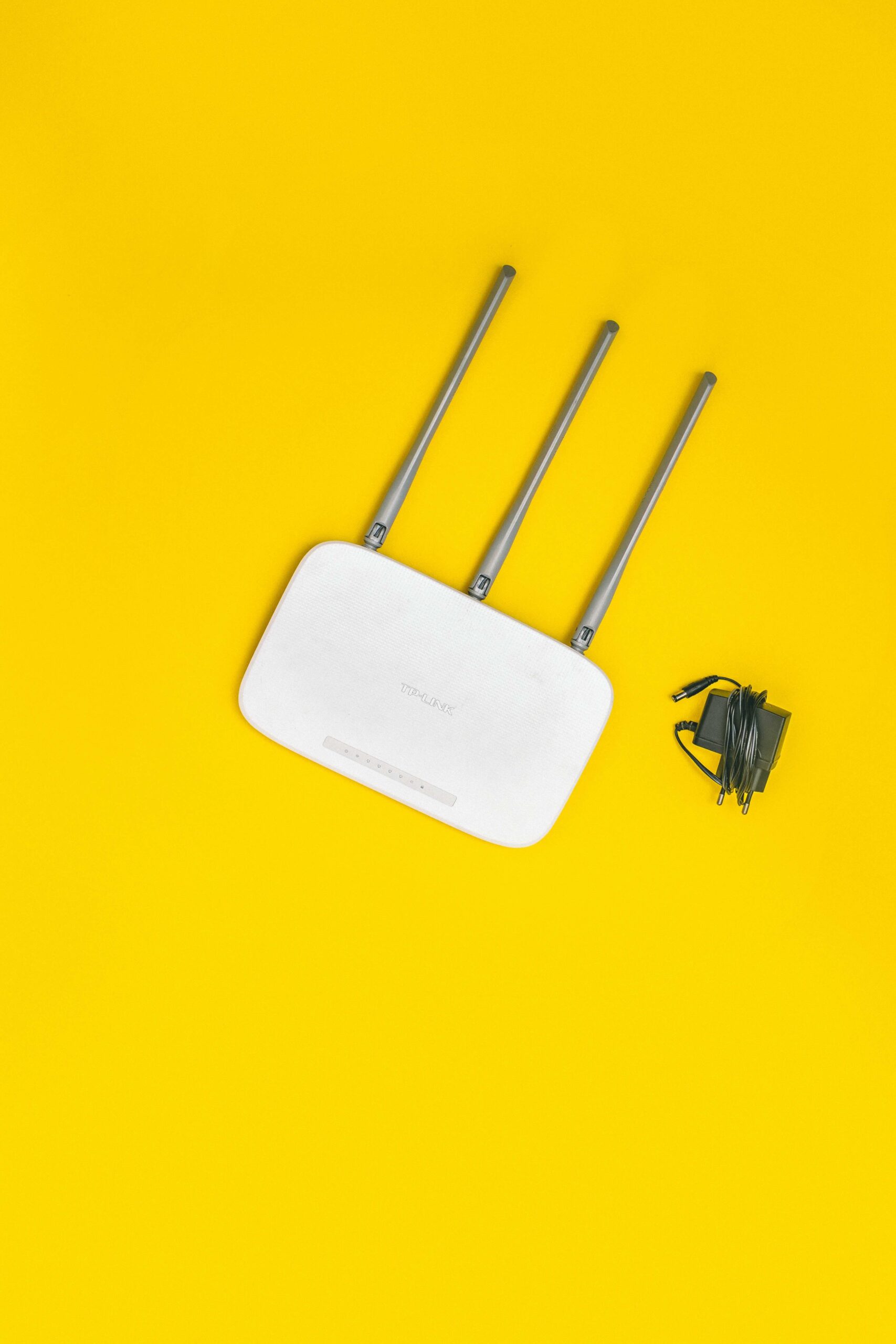 White wireless internet router with charger on yellow background